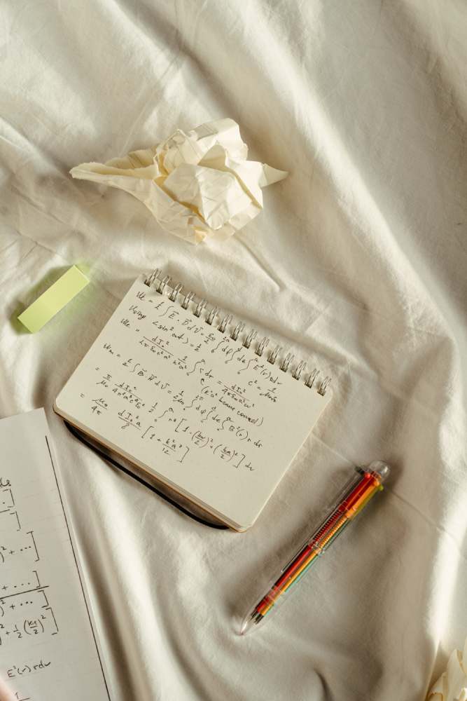 A notebook and pen on the bed